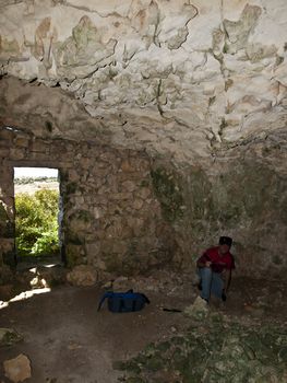 Archeologist examining floor of a troglodyte dwelling cave in Malta