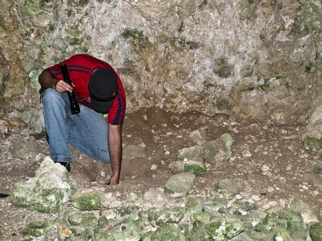 Archeologist examining floor of a troglodyte dwelling cave in Malta