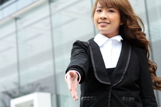 Portrait of a woman with an open hand ready to seal a deal , foucs on her hand.