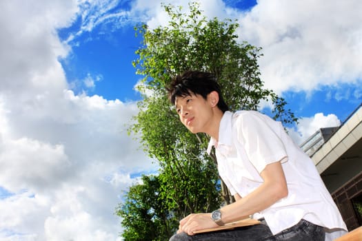 young handsome man sitting and blue sky