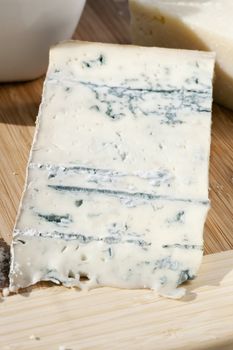 Wedge of gorgonzola cheese on wooden chopping board