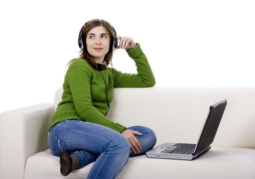 Young woman with headphones and a laptop, seated on a sofa isolated on white