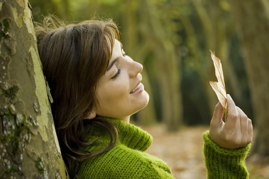 Close-up portrait of a beautiful young woman holding a leaf