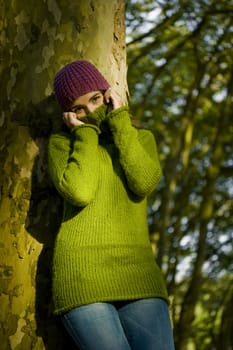 Autumn portrait of a beautiful young woman close to a tree