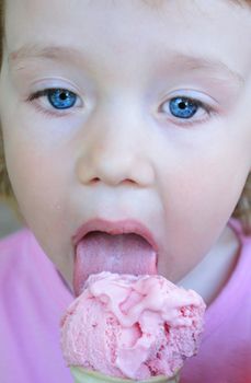 face of little pretty blue eyed girl who is eating  pink ice cream 