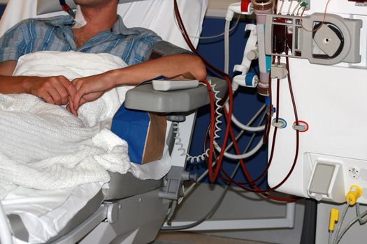 young man attached to dialysis in the renal unit of a hospital
