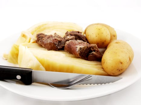 Mutton with cabbage, knife and  fork on white plate towards white background