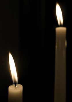 A lit candle over dark background with lot of copy space