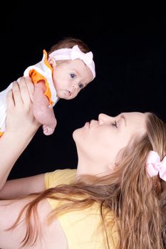 A mother raising her baby up to give the baby a kiss.