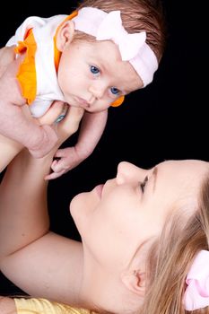 A happy mom holding her precious baby.  The baby looks confused and cute.