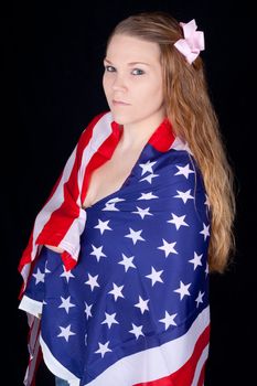 A curious, and sexy woman with the American Flag wrapped and drapped over her shoulders.