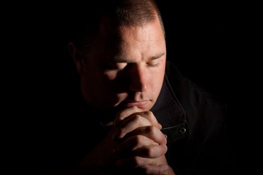 A man praying with holy light coming from above.  He could be worshiping, or just wishing for something.