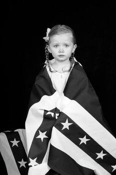 A girl clothed in an American flag design.  The photograph is in black and white.