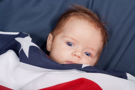A portrait of a baby covered by an american flag.