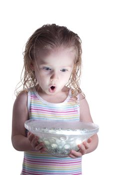 A young child is excited and enchanted by the ball of light glowing in the glass bowl she is holding.