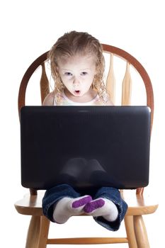 A young child is wowed by what is coming out of her computer screen
