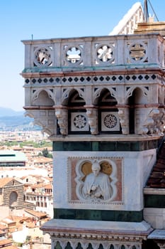A tower with a statue on the foof of Basilica di Santa Maria del Fiore 
