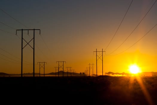 A beautiful morning sunrise on the field.  The power lines attract the viewers eye through the field.