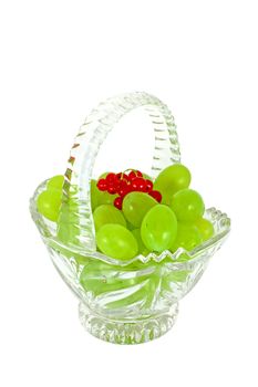 Glass basket full of fresh grapes and currants isolated on white