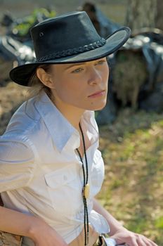 Portrait of a woman in a white shirt and cowboy hat on a ranch.