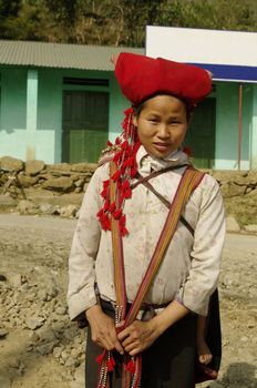Nearly SAPA, City of North Vietnam. A woman of the ethnic (minority) Hmong Red pompoms with her baby in the back. She wears her beautiful costumes and hairstyle typical.