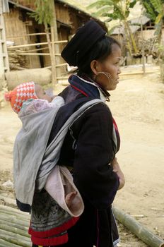 A Black Dao woman and her baby. All women carry their baby in the back. They are well all day, despite the hard work the fields, rocked back on their mother