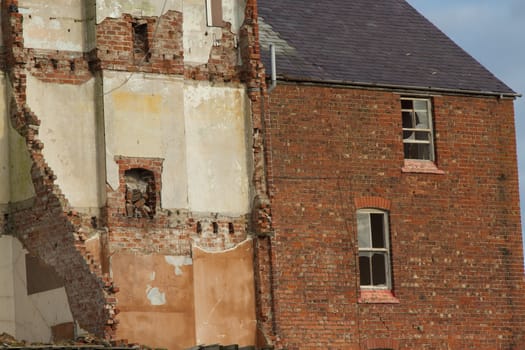 The remains of a demolished building with broken windows crumbled brick walls and fireplaces.