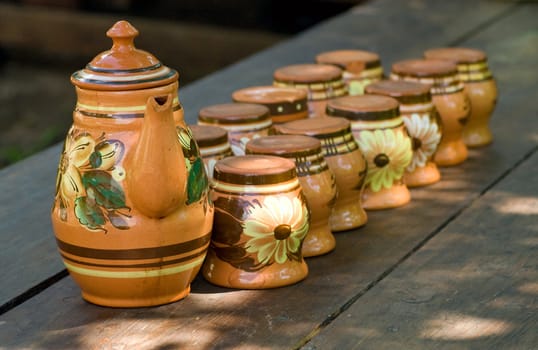 teapot and twelve  caps on a wood table at  a synny day