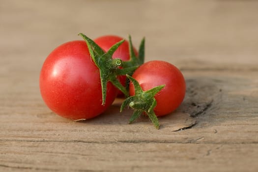 Small red cherry tomatoes on a wood table.  Daily light