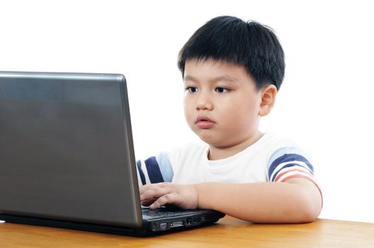 A elementary schoolboy using a laptop over white background.