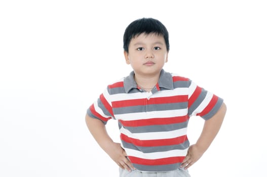 Portrait of a gloomy elementary schoolboy with hands on his hip, over white background.