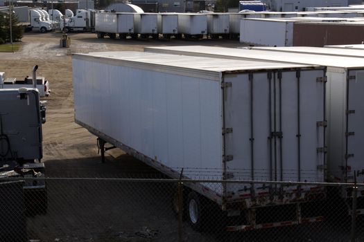 A parking lot with lots of transport trucks and trailers.