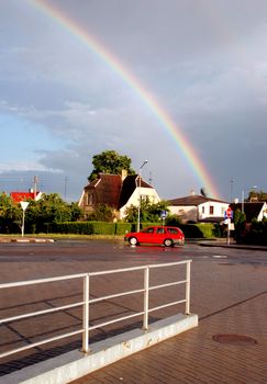 Over the red car and a white houses rainbow is much nicer