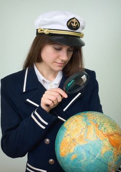 Sea captain looks at the globe through a magnifier