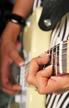 woman plays an electric guitar, images is selective focus on the neck hand