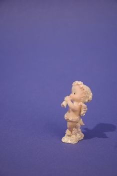 Figure of little angel with a trumpet isolated on a blue background