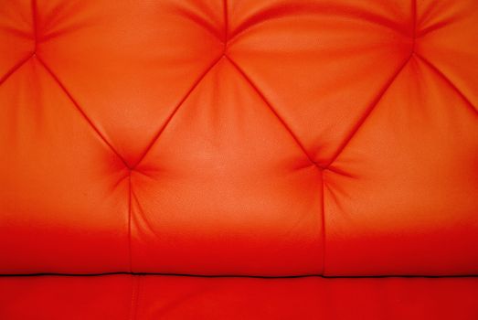 Stitchings on background of horizontal red leather couch