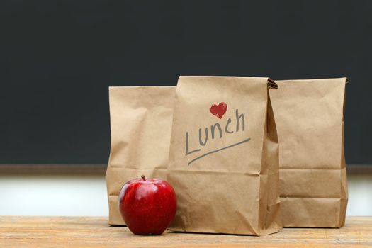 Paper lunch bags with red apple on school desk