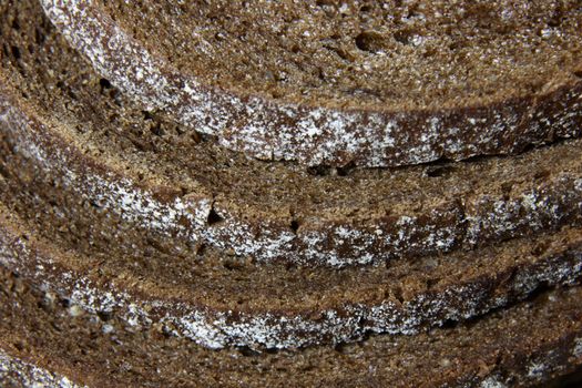 A close-up of the crusts of five slices of pumpernickel bread.
