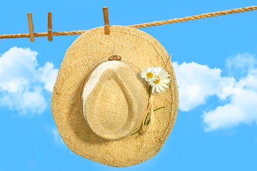 Straw hat on clothesline with blue sky