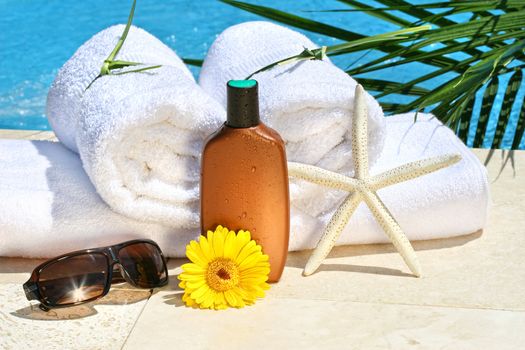White spa towels and tanning lotion by the pool