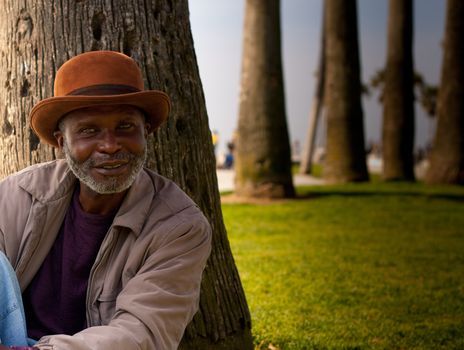 A man sitting in a park near the beach.  You can see deep into his eyes!