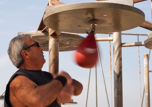 A boxer punching a speed bag in the park.