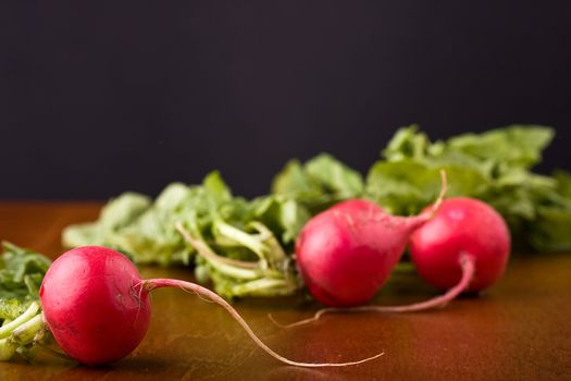 radish on a wood cutting board leaves and roots