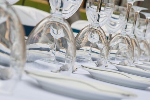Close-up of a wedding receptions' dinner table with plates, water & wine glasses lined up into the distance.
