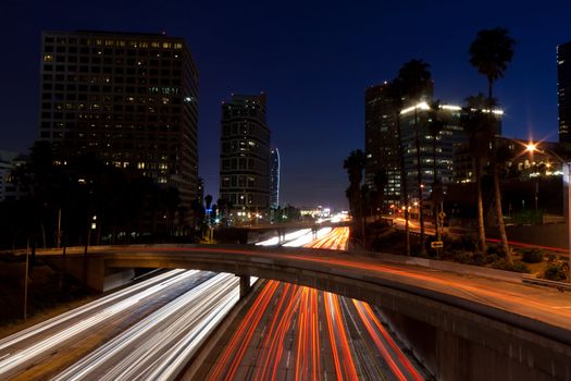 A photograph of the night blue sky of Los Angeles California.  The trafic is streaking across the roads.