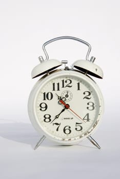 Old white mechanical alarm clock on a white background