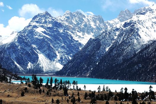 Landscape of blue lake and mountains covered with snow in winter