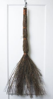 A handmade cinnamon broom hanging on a door.