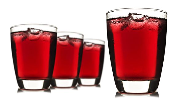 Four glasses of red fruit juice with ice on white background